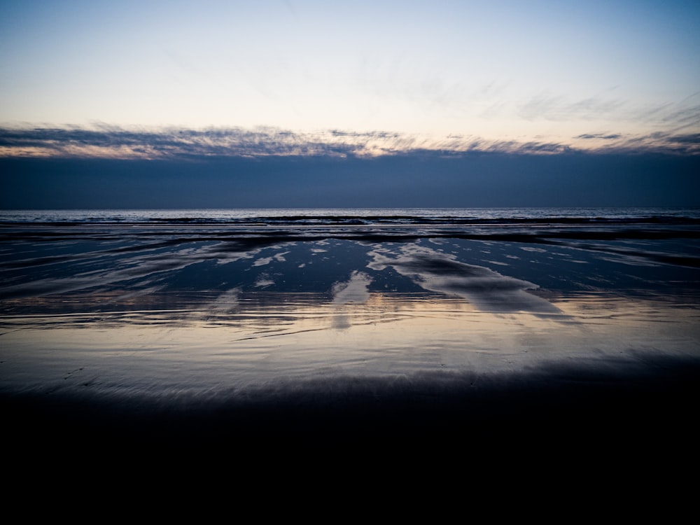 the sky is reflected in the water on the beach