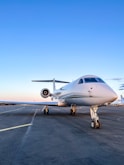 A private jet ready for takeoff on a pristine runway with a clear blue sky.