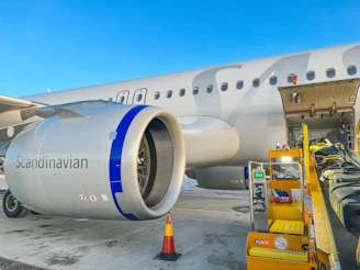 A sleek cargo airplane being loaded securely at an airport under clear skies.