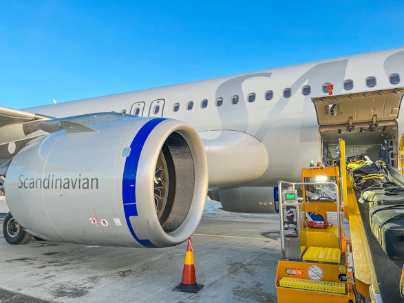 A sleek cargo airplane being loaded securely at an airport under clear skies.