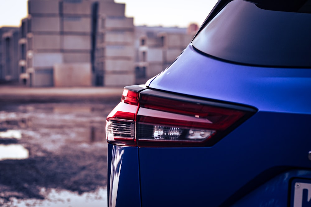 the back end of a blue car parked in a parking lot