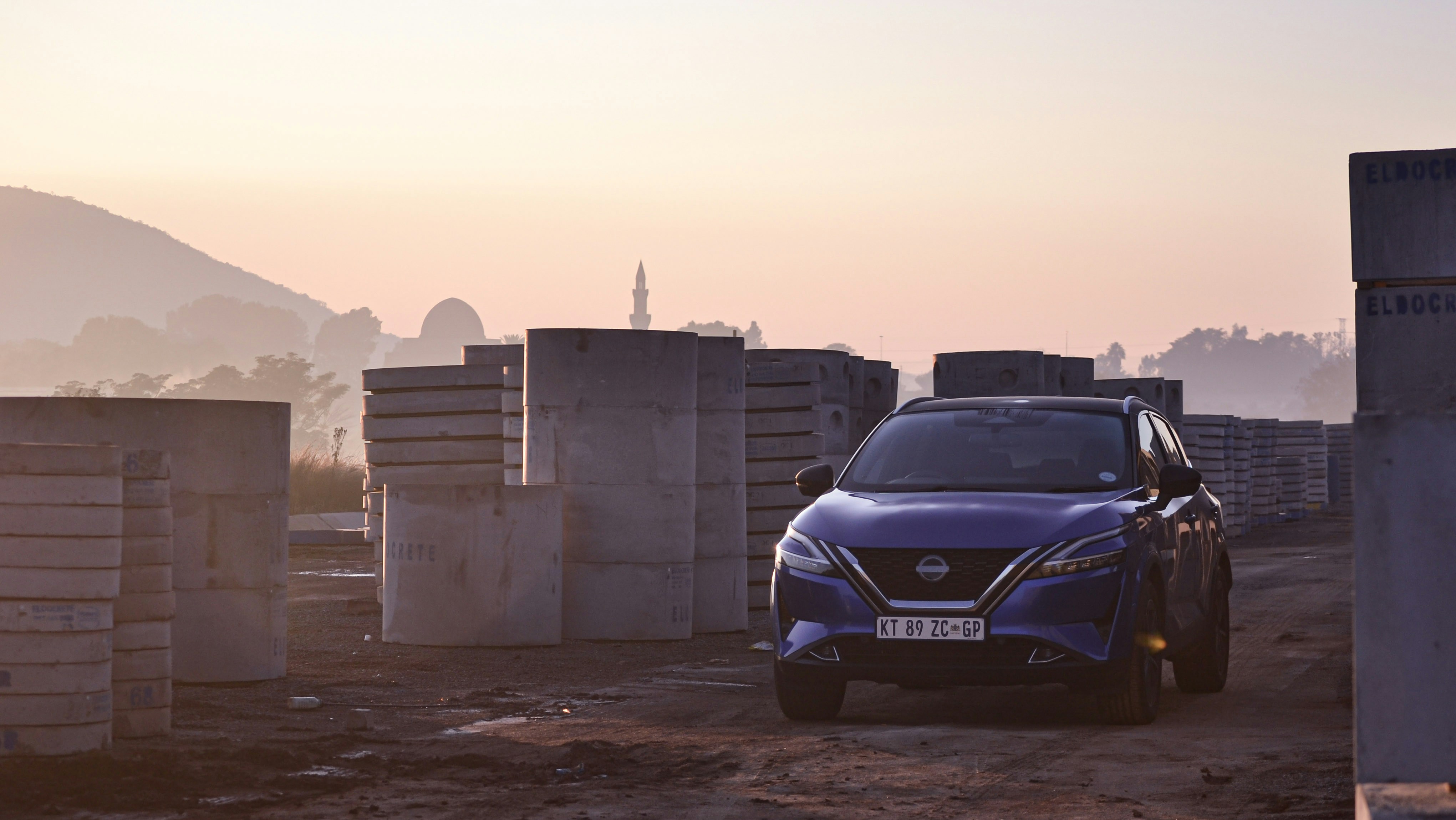 a blue car parked in front of a pile of concrete