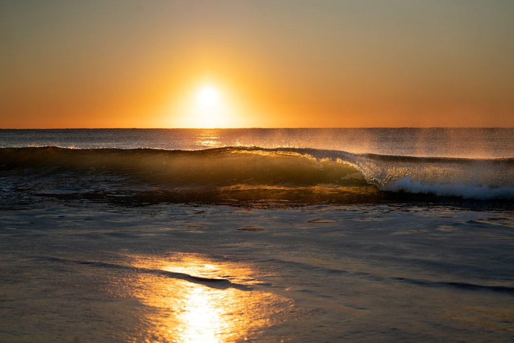 the sun is setting over the ocean waves