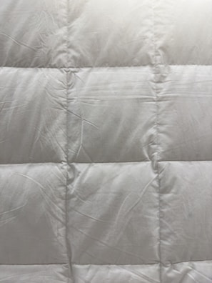 a close up of a bed with a white comforter