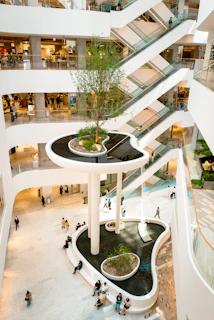 Spacious shopping mall atrium featuring towering artificial flower displays that maintain vibrant color without maintenance.