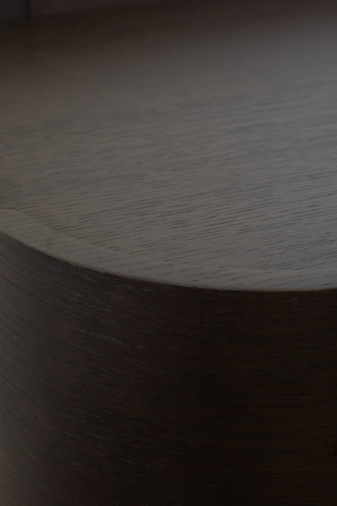 Close-up of a dark walnut tabletop showing deep grain under directional light