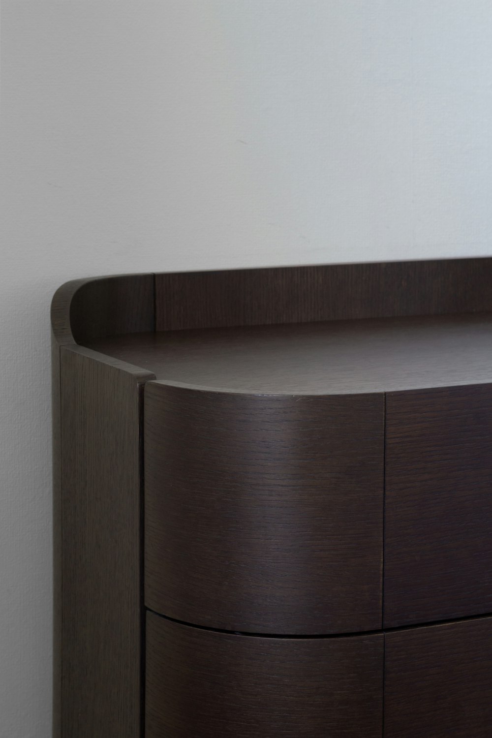 a close up of a wooden dresser with a white wall in the background