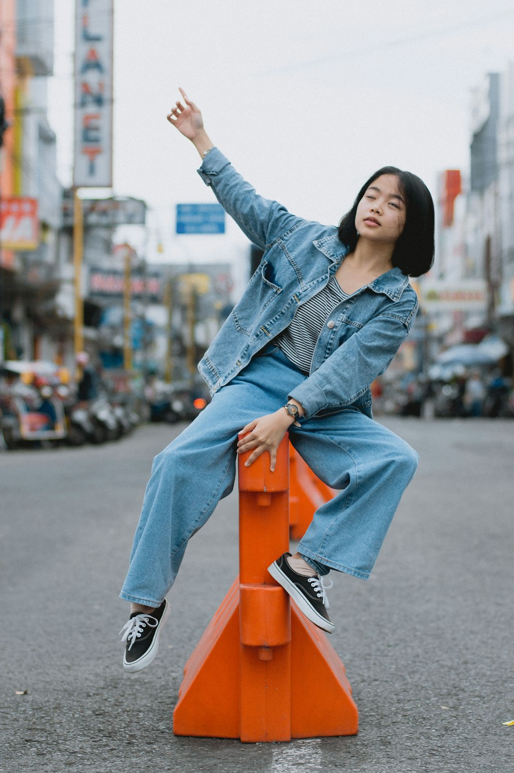 a woman sitting on top of an orange traffic cone