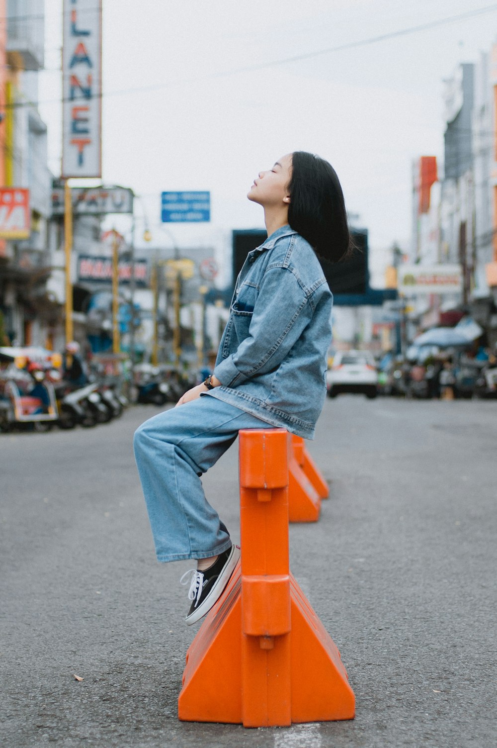 a woman sitting on top of an orange traffic cone