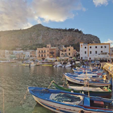 A cozy Maltese seaside village with colorful boats bobbing in the harbor at sunset.