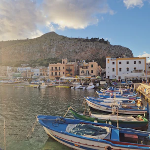 A cozy Maltese seaside village with colorful boats bobbing in the harbor at sunset.