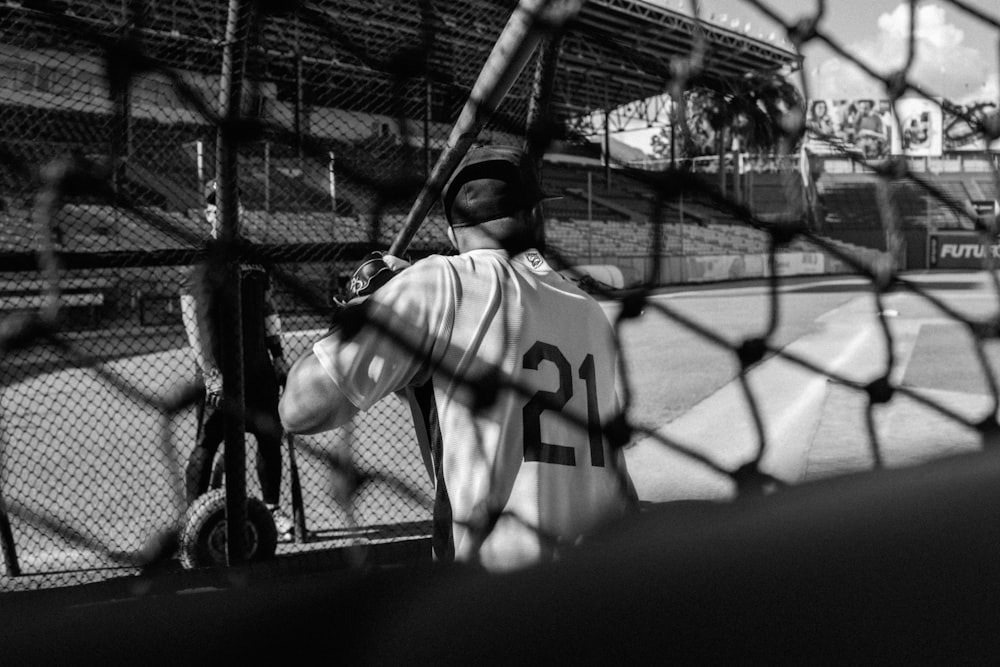 a man holding a baseball bat standing next to a fence