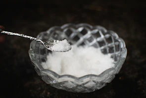 Close-up of delicate flor de sal crystals resting on a rustic wooden spoon.