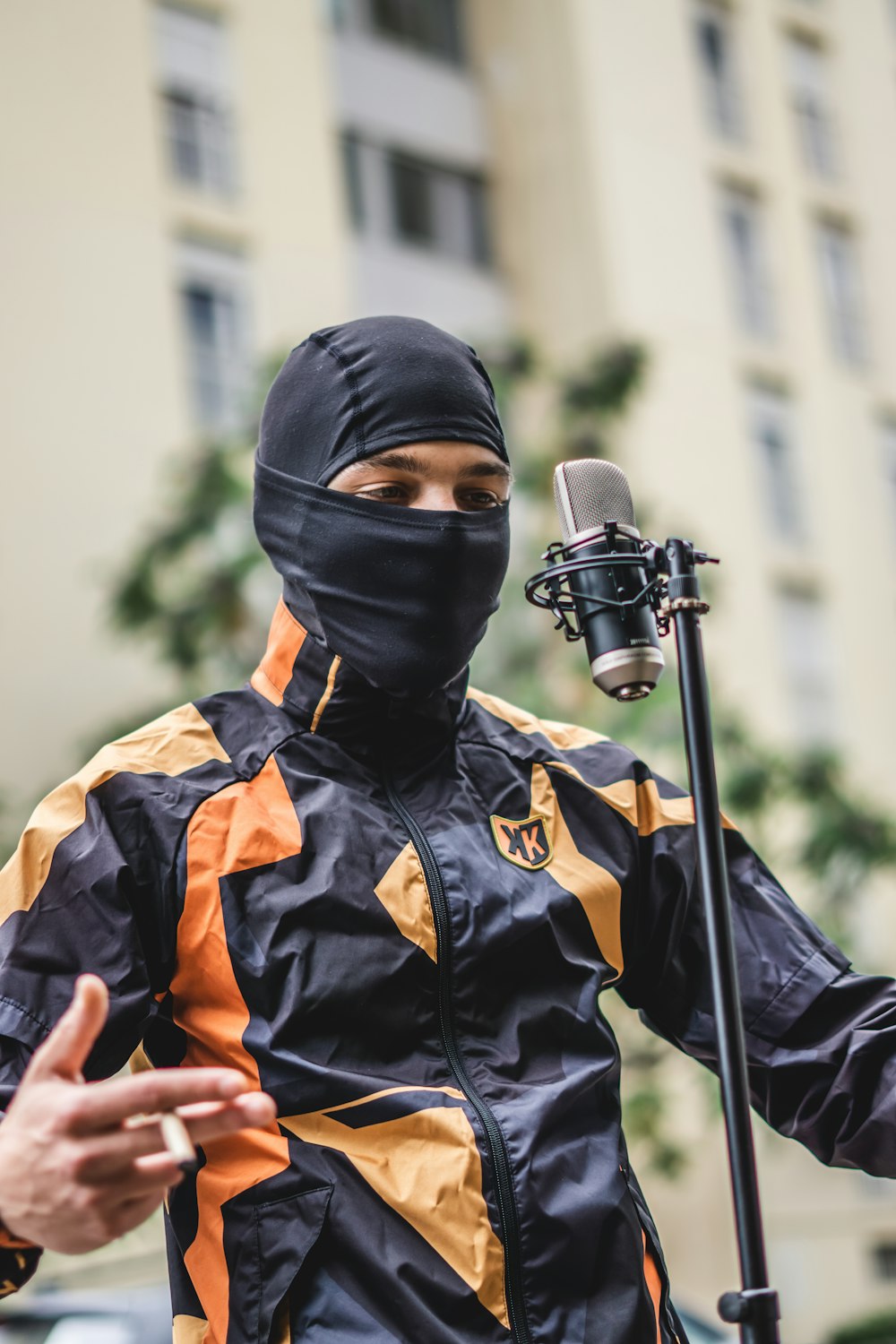a man in a black and orange outfit holding a microphone
