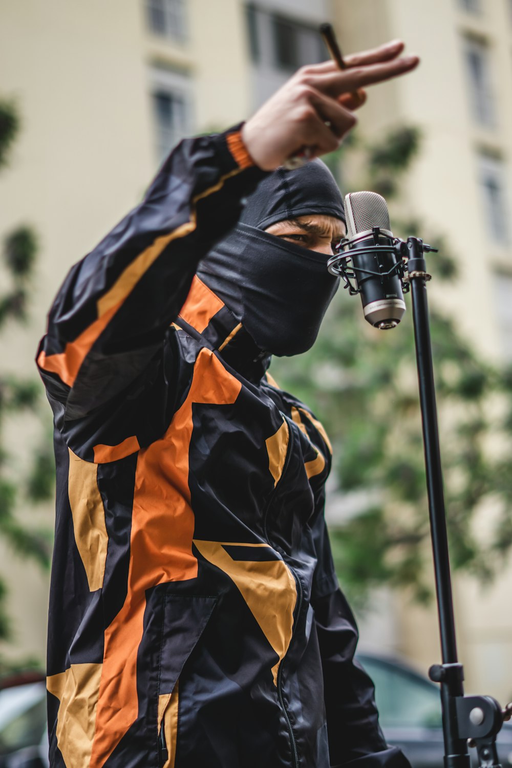 a man in a black and orange jacket holding a microphone