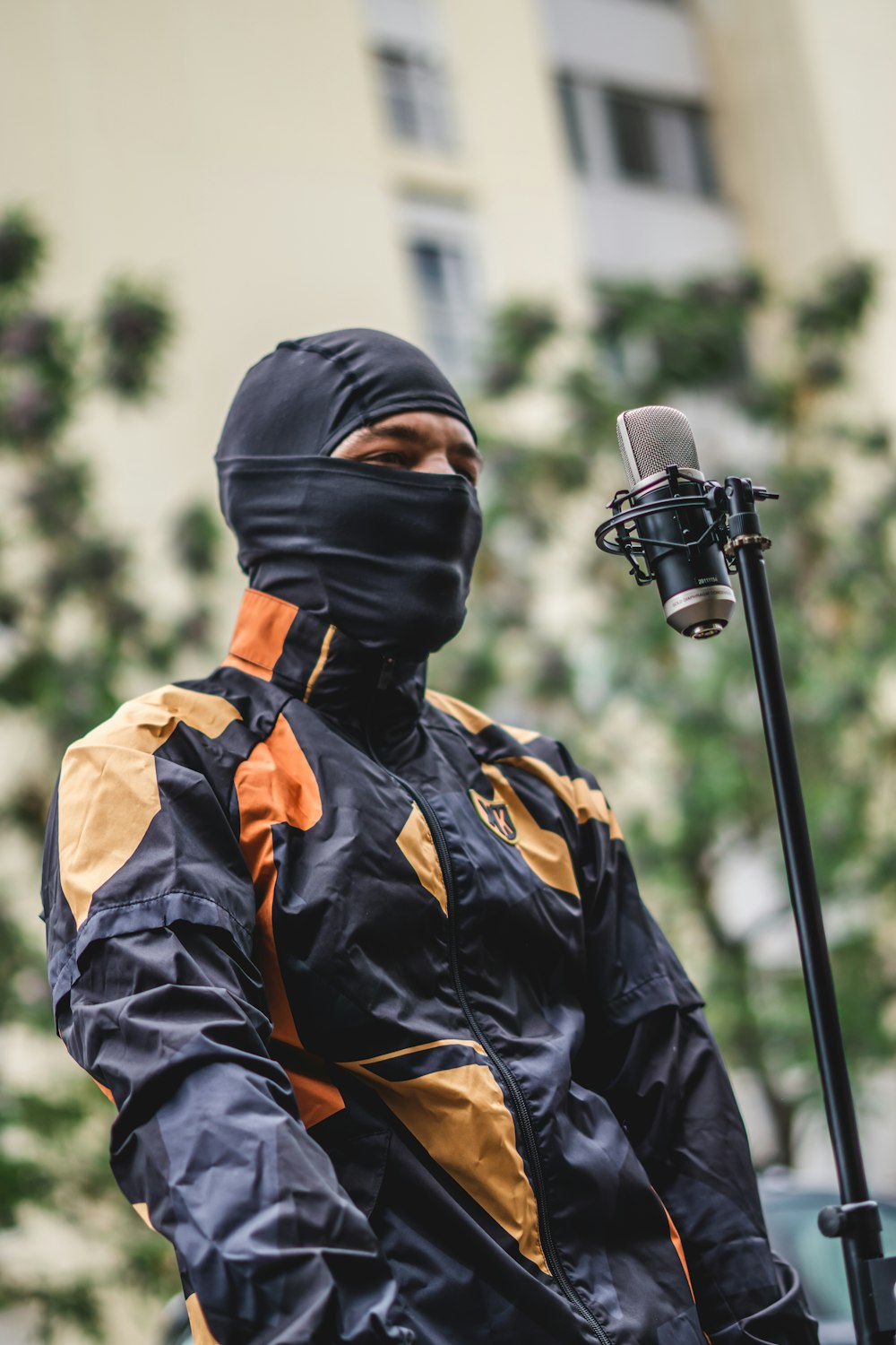 a man in a black and yellow jacket holding a microphone