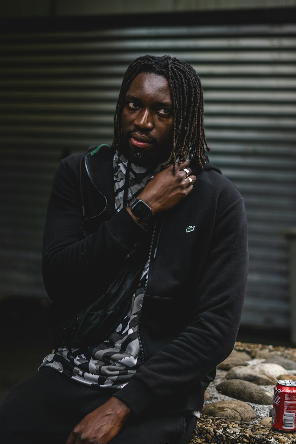 a man with dreadlocks sitting on a rock