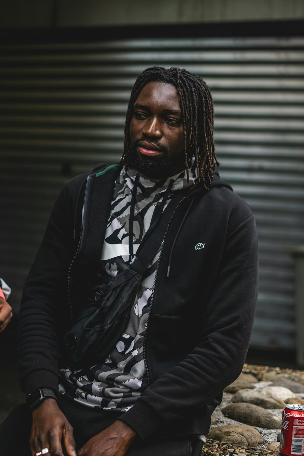 a man with dreadlocks sitting on a rock