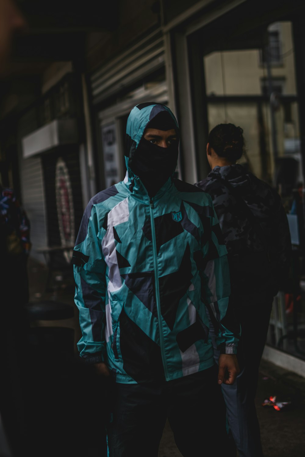 a man in a blue and black jacket standing on a sidewalk