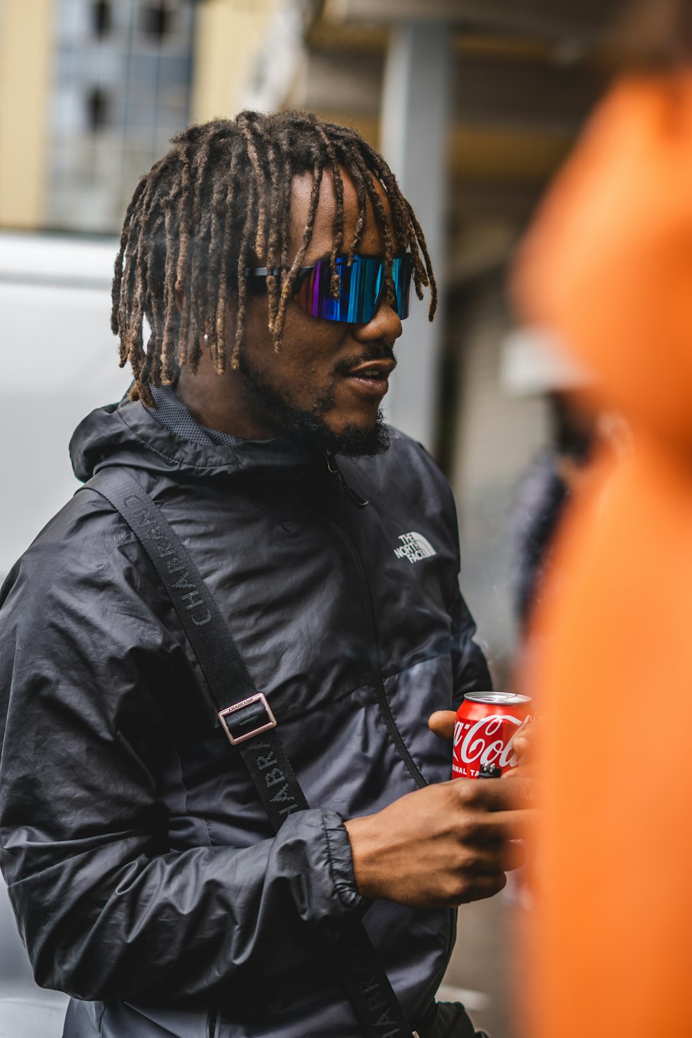 a man with dreadlocks holding a can of coke