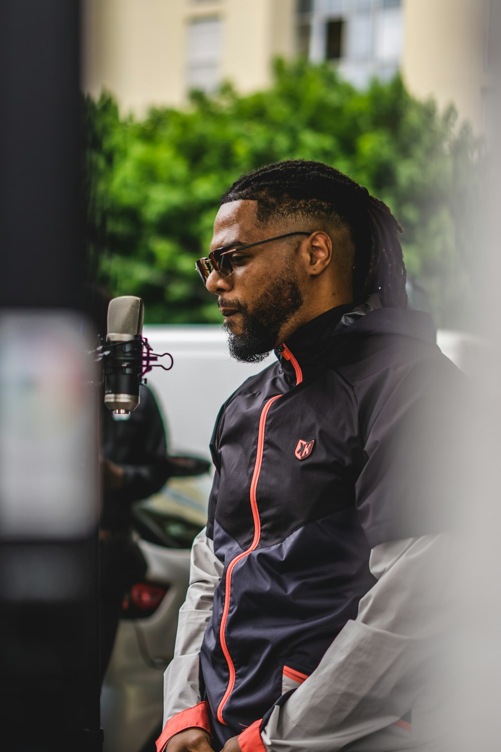 a man with a beard and glasses sitting in front of a microphone