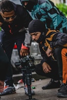 A group of diverse students gathered around a film camera, learning to shoot a hip hop music video.