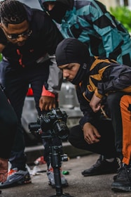 A small group gathered outdoors with cameras, focusing on a tutor explaining camera settings.