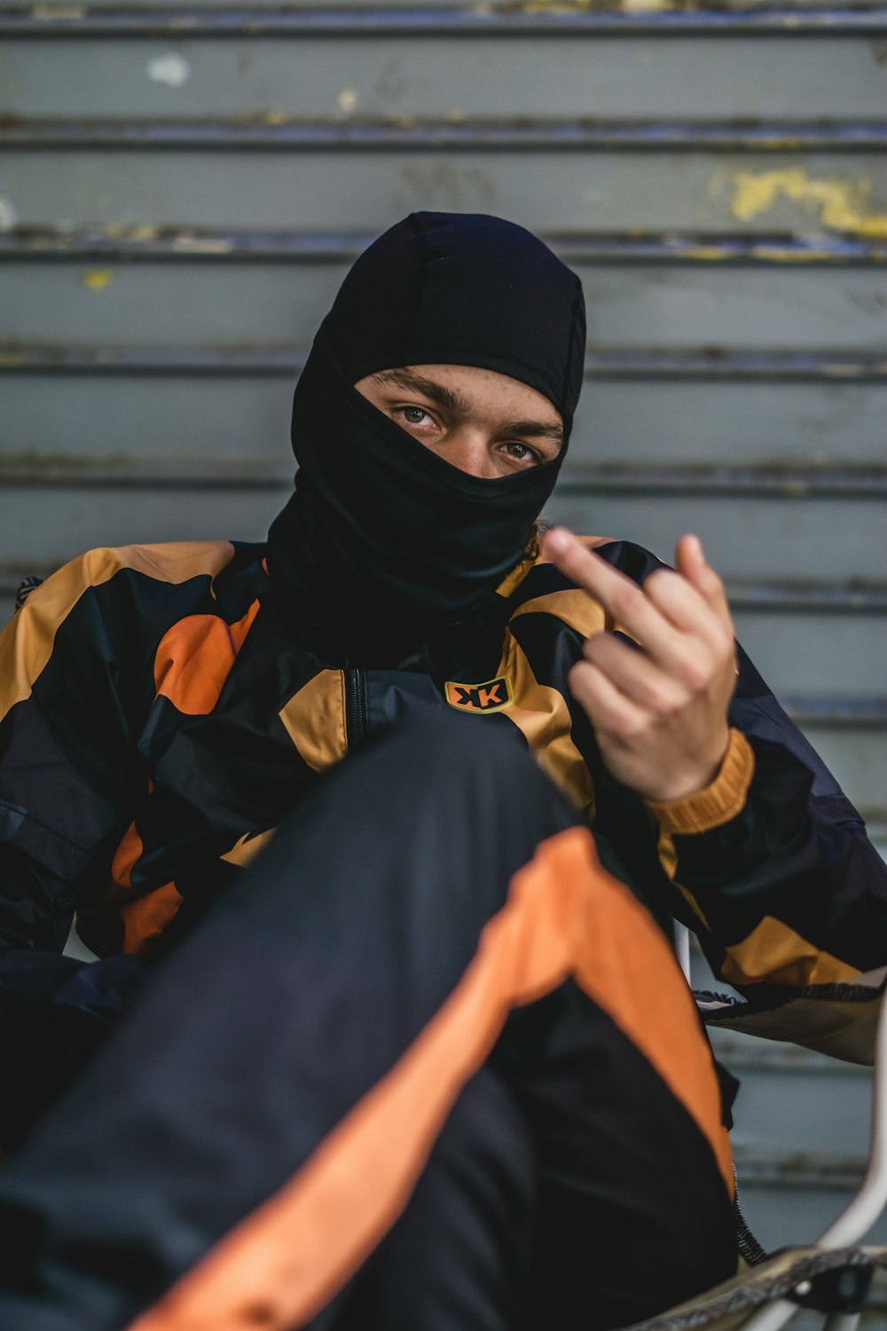 a man wearing a black and orange jacket and a black head scarf