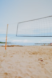 a volleyball net on a beach with people in the background