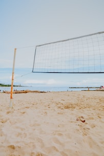 a volleyball net on a beach with people in the background