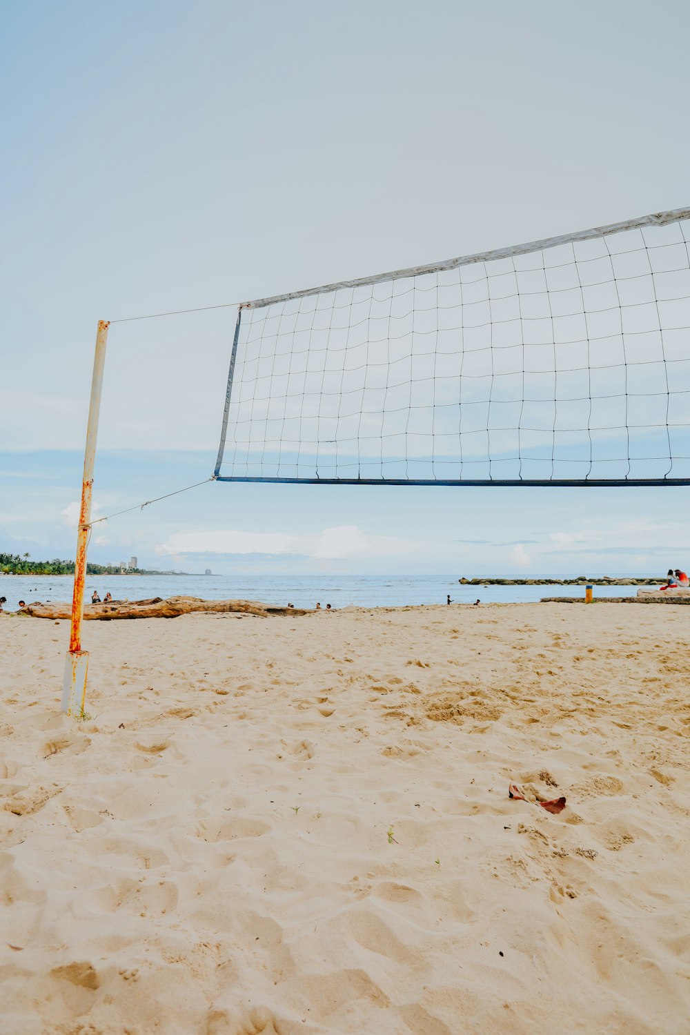 a volleyball net on a beach with people in the background