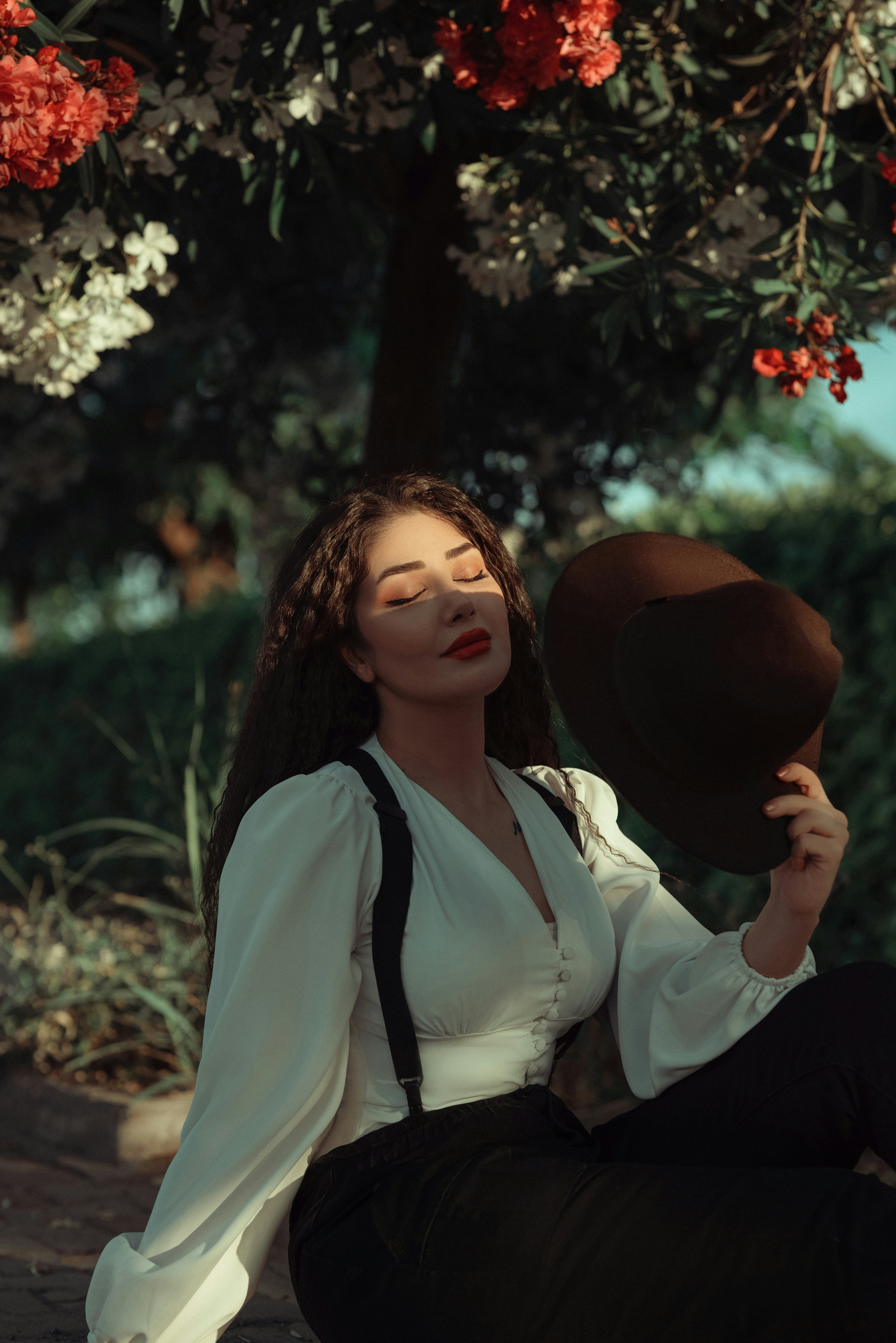 머리에 모자를 쓰고 나무 아래에 앉아 있는 여자