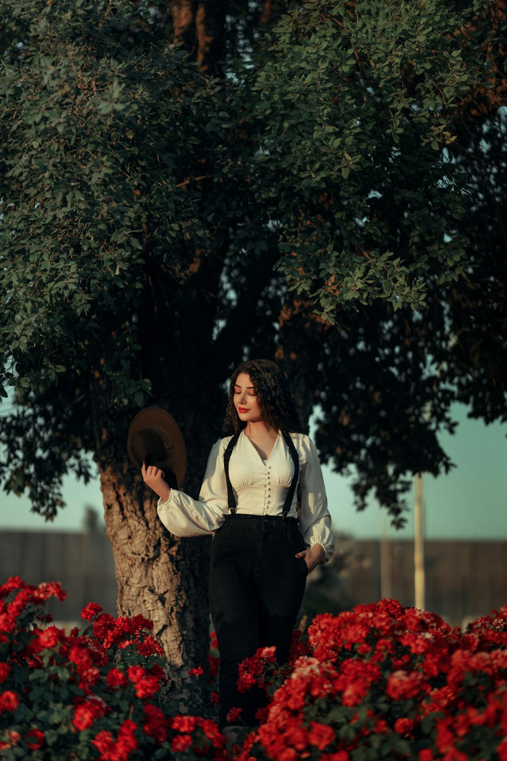 a woman standing next to a tree with a hat on her head