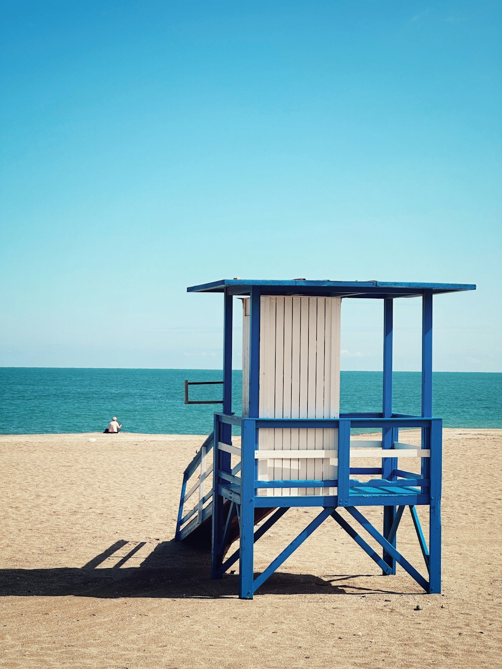 Una sedia di salvataggio blu e bianca su una spiaggia