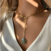 Lifestyle shot of a woman wearing Lakenza jewelry in a softly lit, modern interior.