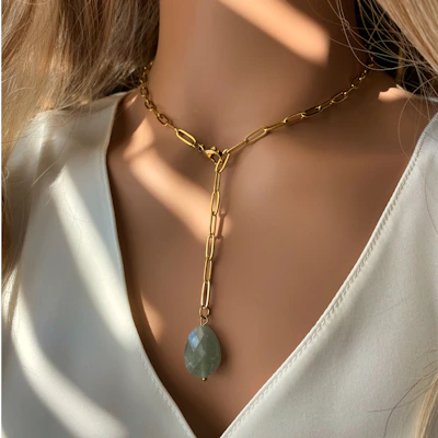 Close-up shot of a delicate 18k gold plated necklace with intricate detailing, reflecting ambient warm light, set against a soft fabric backdrop.