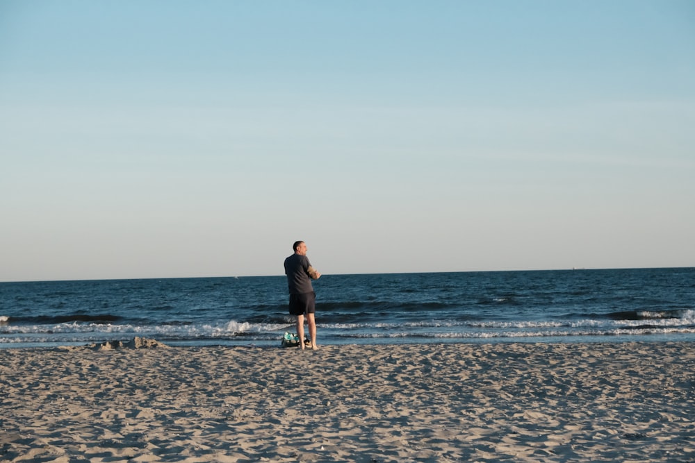 a man standing on top of a sandy beach next to the ocean