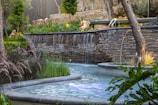 A backyard garden with a small pond and a cascading multi-tiered water feature.