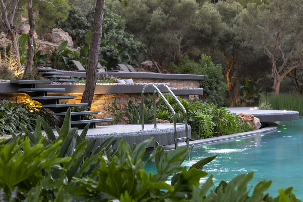 a pool surrounded by trees and plants next to a hillside