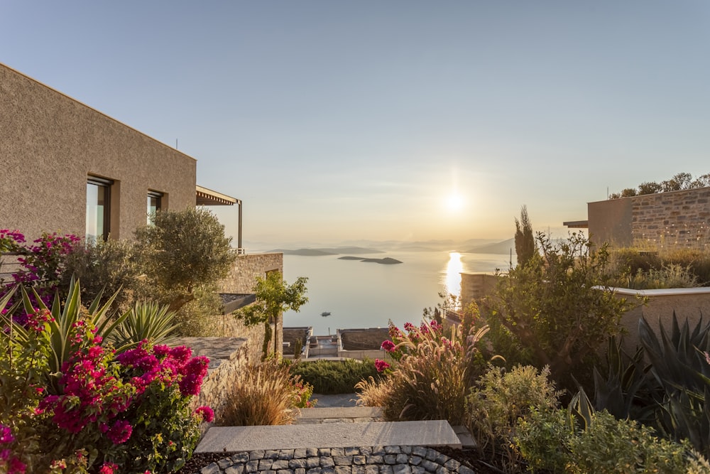 the sun is setting over the water from a house