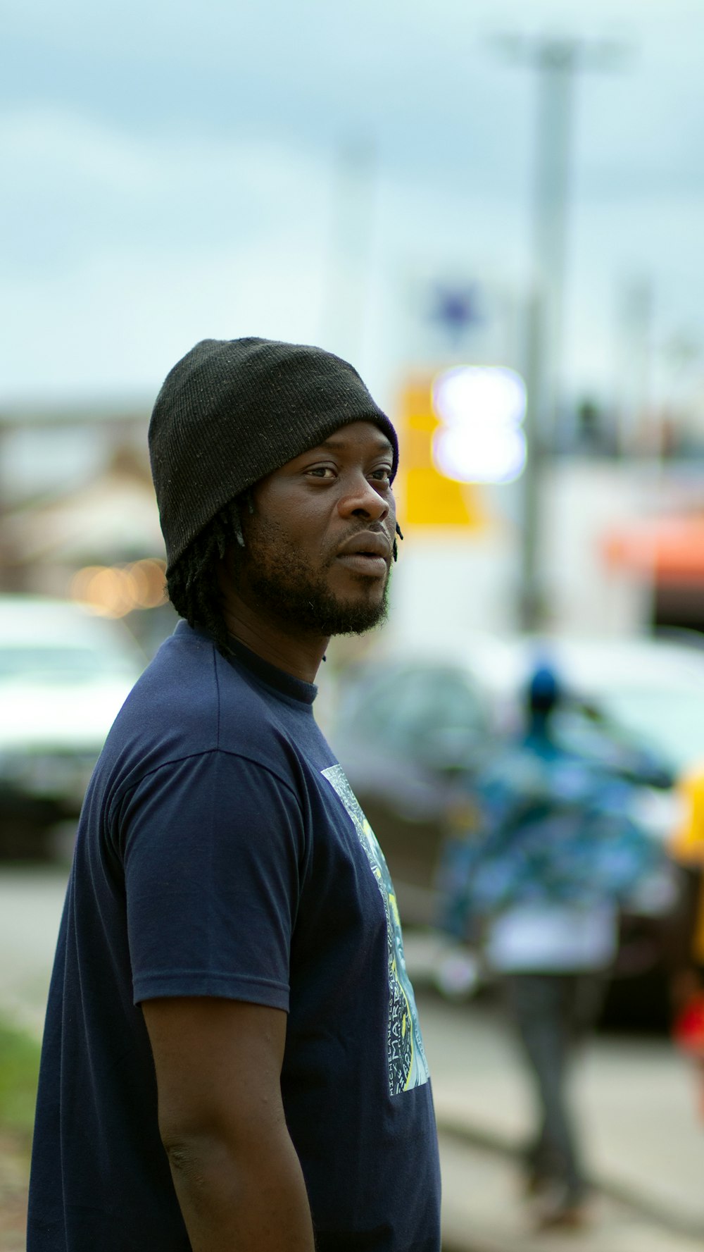 a man with a beanie standing on a sidewalk