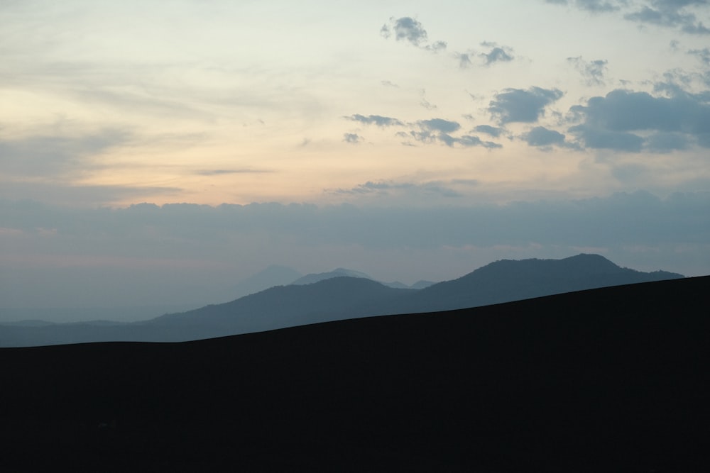 the silhouette of a mountain range against a cloudy sky