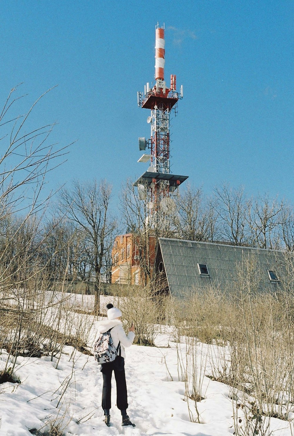 a person standing in the snow near a tower