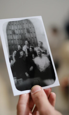 A lively group posing happily inside a classic photobooth with printed strips in hand.