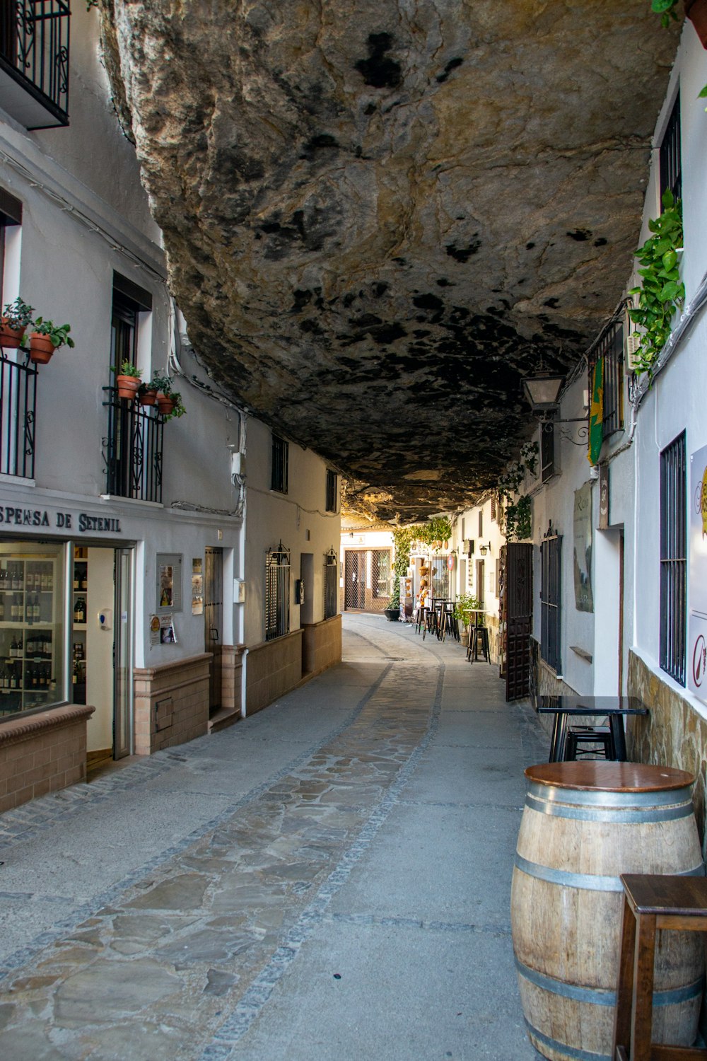 a narrow street with a large rock hanging from the ceiling