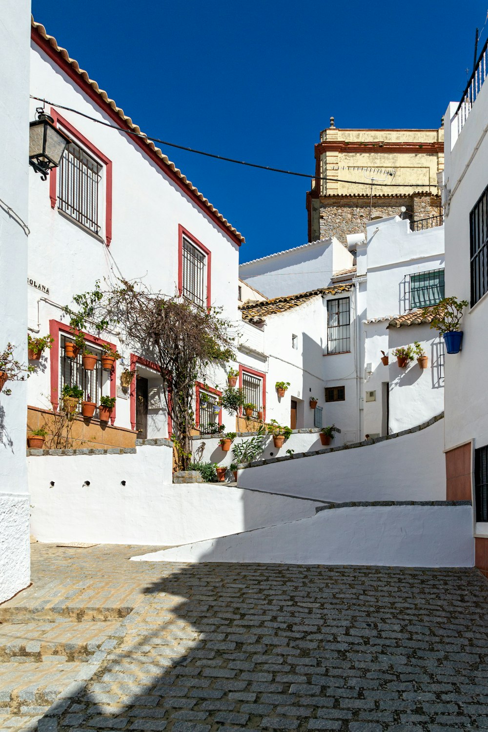 a cobblestone street lined with white buildings
