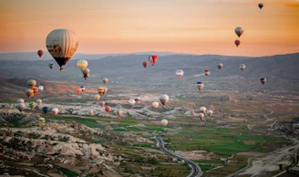 Colorful hot air balloons floating over the rocky fairy chimneys of Cappadocia at sunrise.
