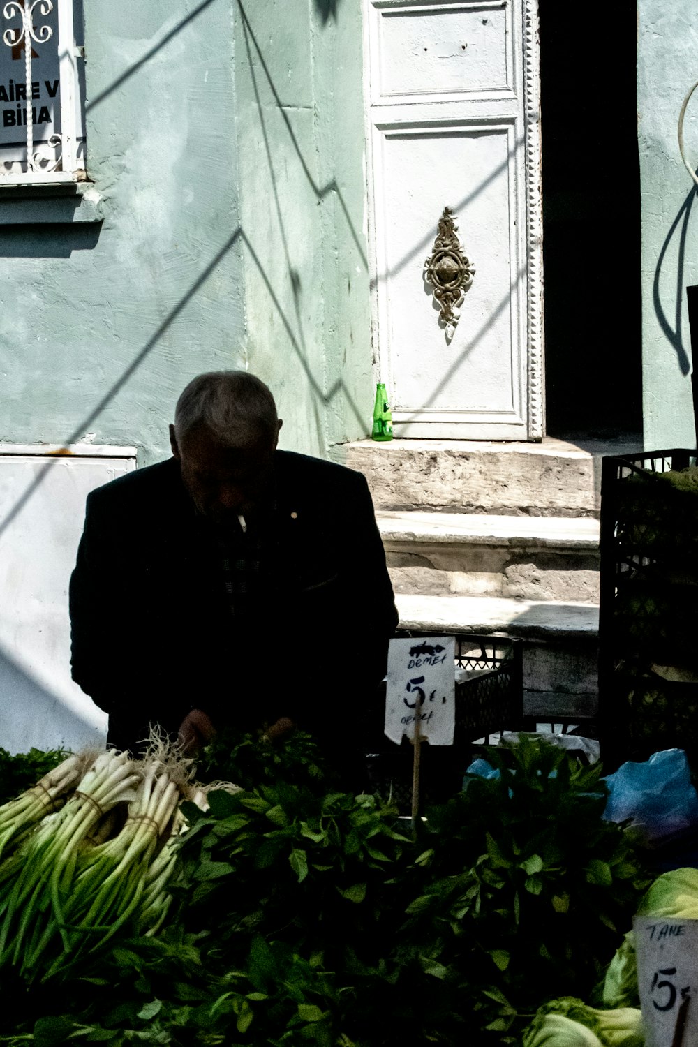 a man standing next to a pile of green vegetables