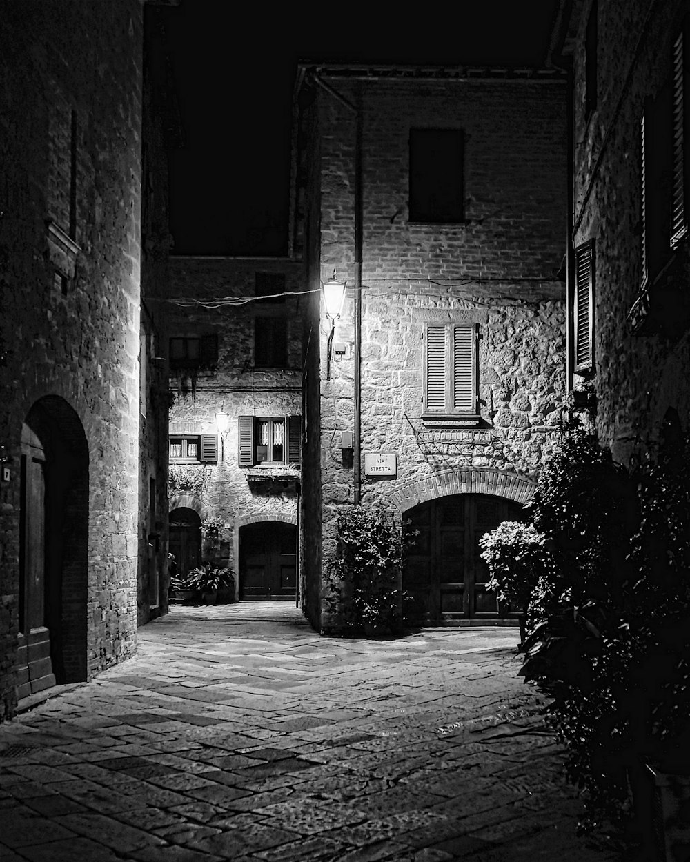 a black and white photo of an alleyway at night