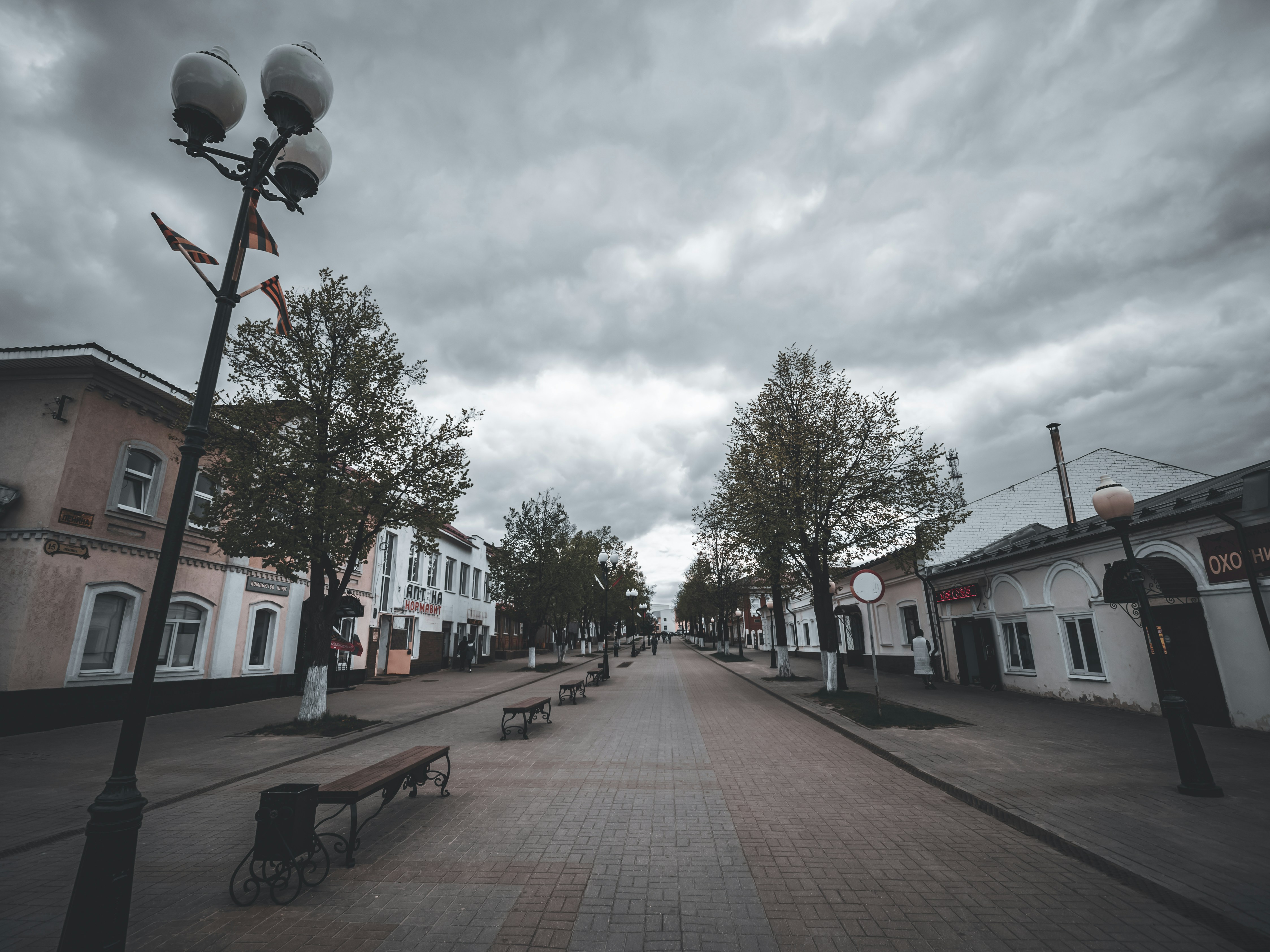 an empty street with benches and street lights